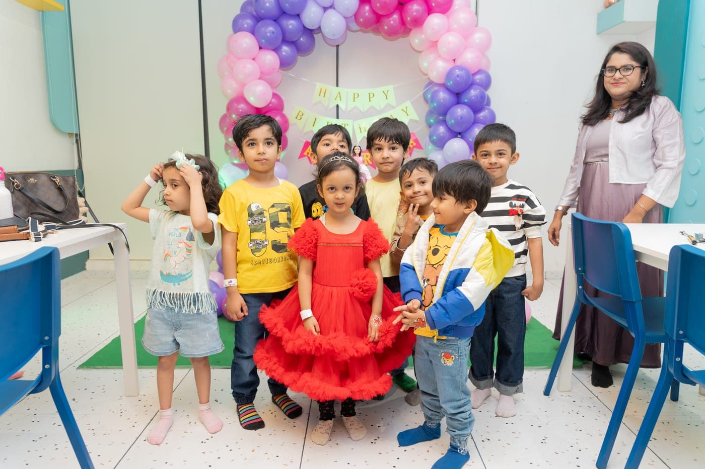 Kids posing together in front of a balloon arch at a birthday party