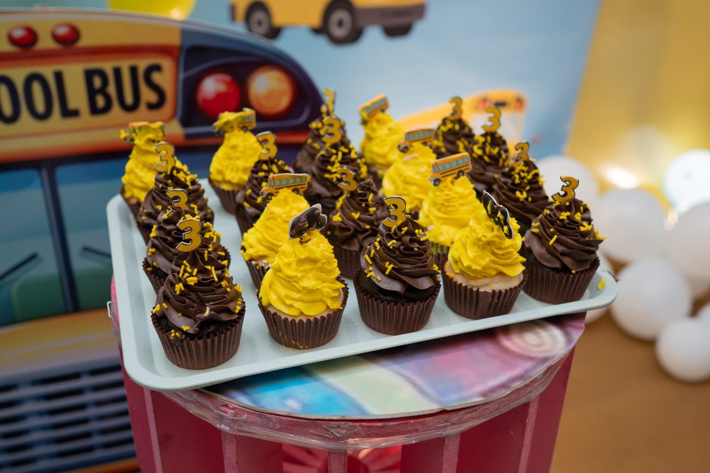 Tray of chocolate and yellow birthday cupcakes with number 3 toppers