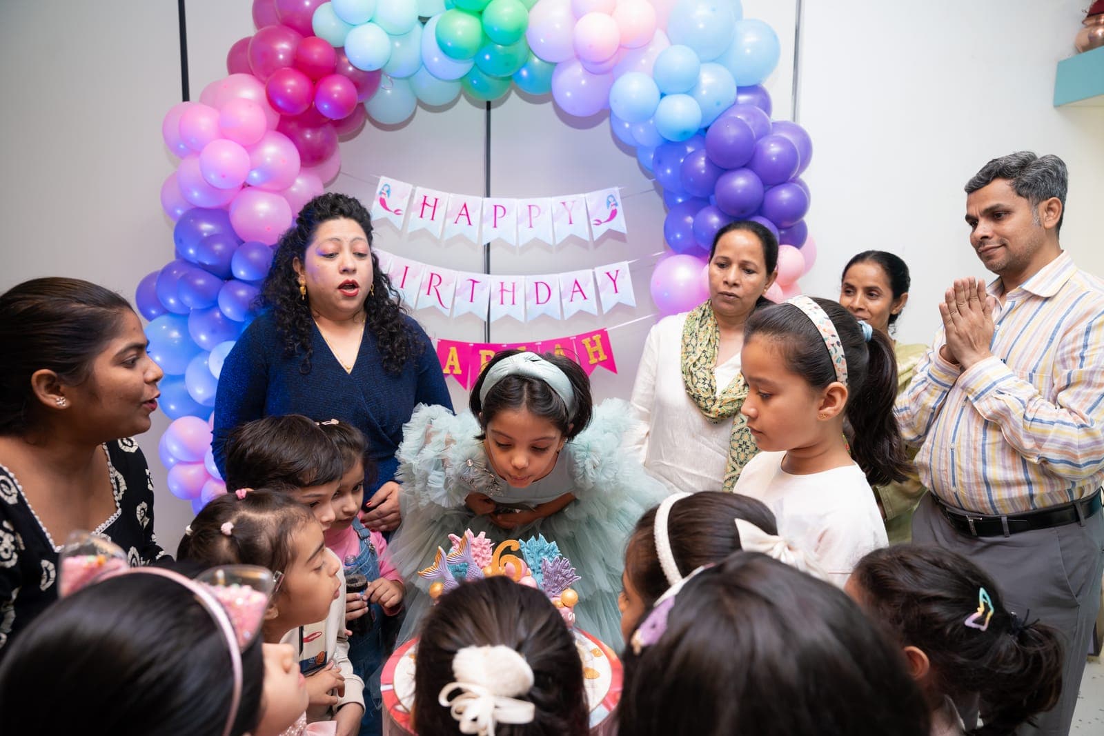 Birthday girl surrounded by family and friends at cake time