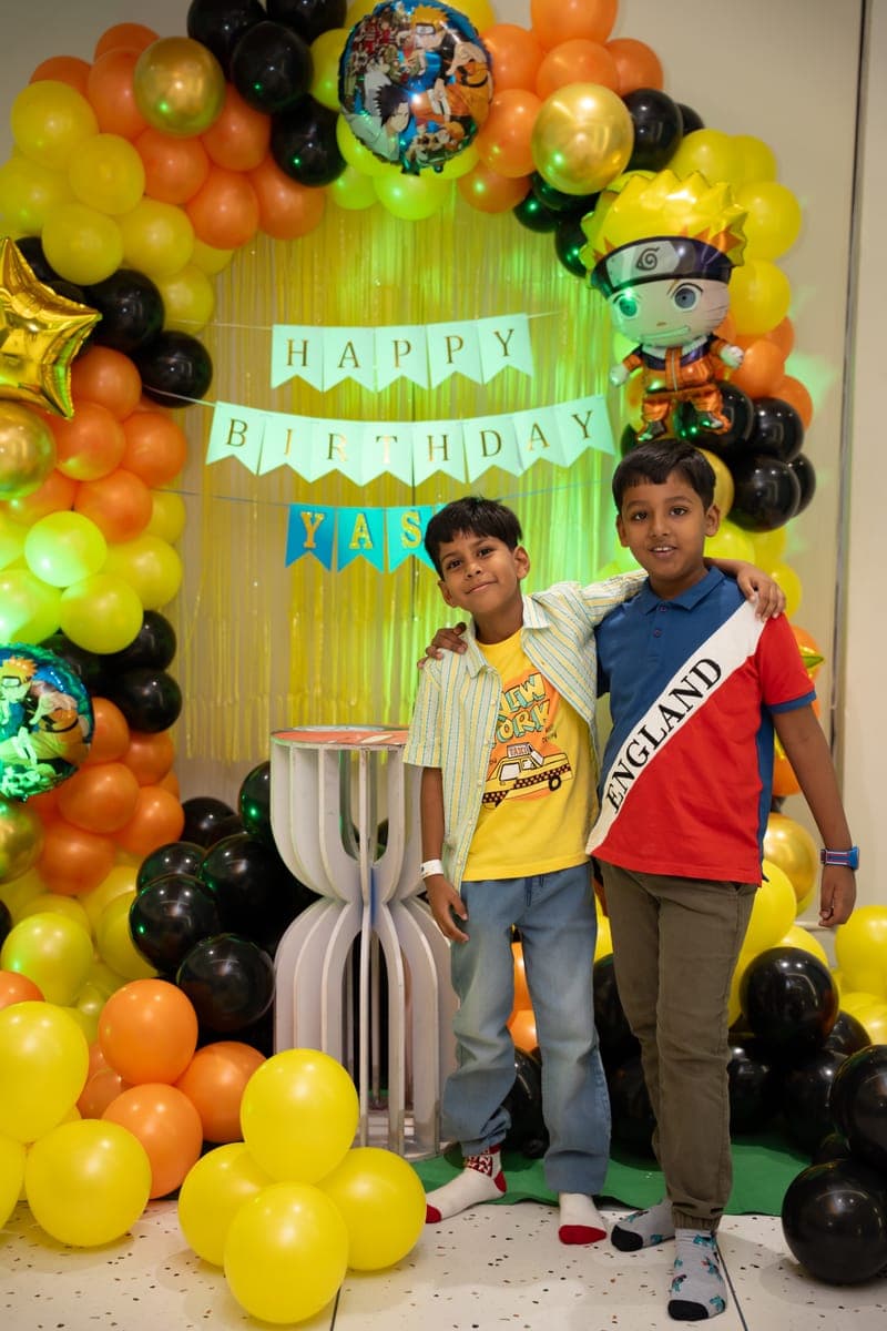 Yash and a friend at his Naruto-themed birthday balloon arch