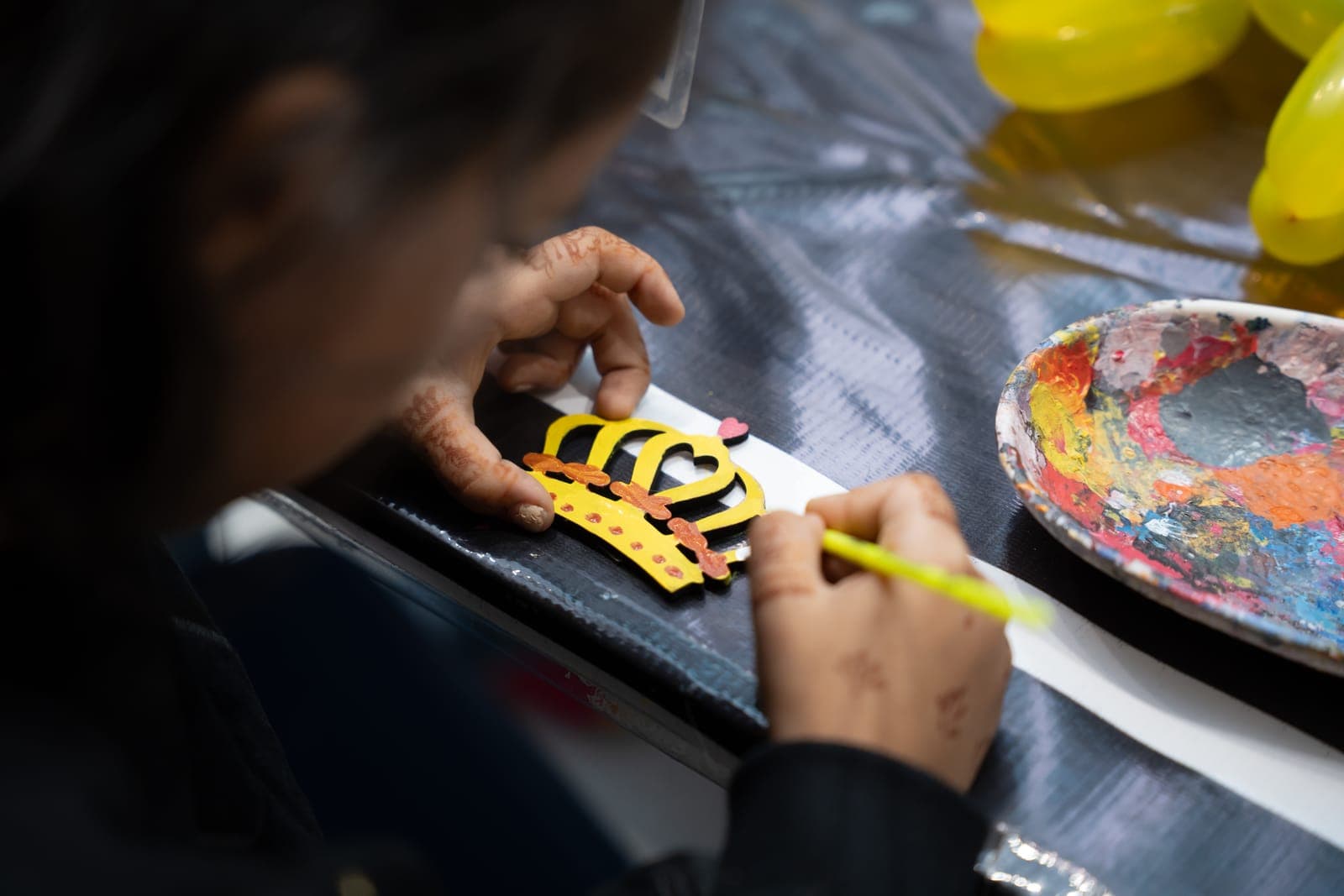 Child painting a paper crown in a craft workshop