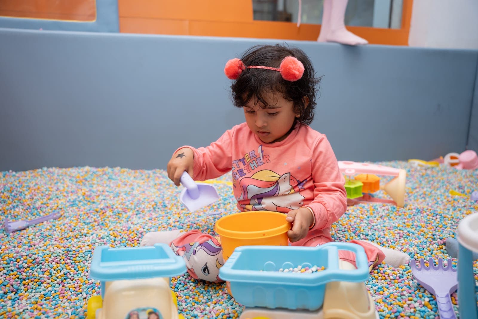 Toddler scooping in the sensory pit
